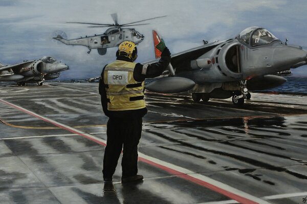 Un hombre con un chaleco amarillo y una bandera. En el fondo, aviones de ataque av - 8B