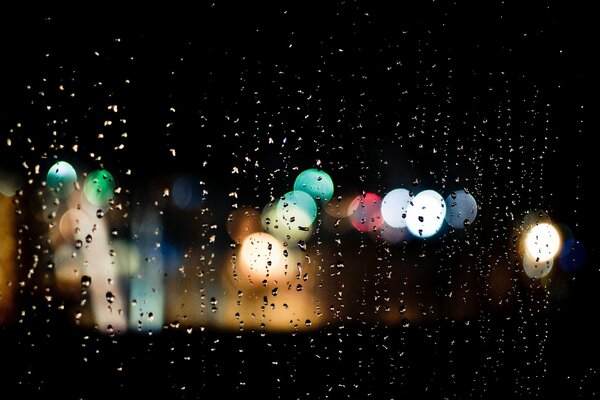 City lights through raindrops on glass