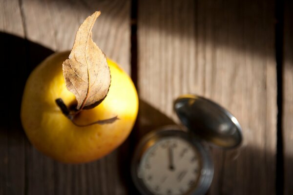 Jabłko z liściem i zegarem na drewnianym stole