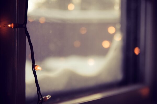 Snow on the window and lights garlands