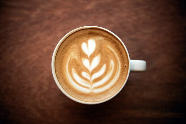 Taza de café cappuccino con espuma y patrón de flor de corazón