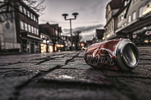 An empty can of Coca-Cola on the background of the pavement