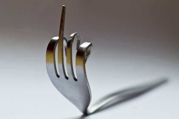 Art macro shooting of a fork on a white-gray background