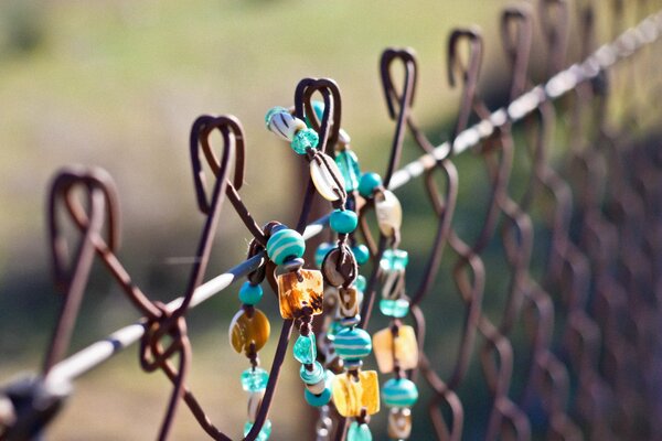 An accessory made of beads- a bracelet on a fence net