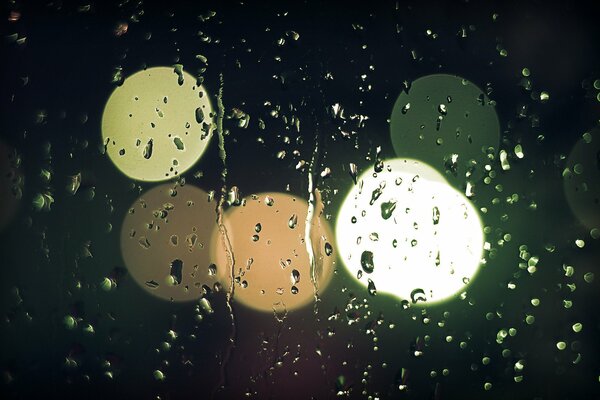 Gocce di pioggia su vetro e luci