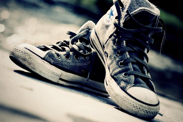 Vecchie scarpe da ginnastica con lacci sull asfalto