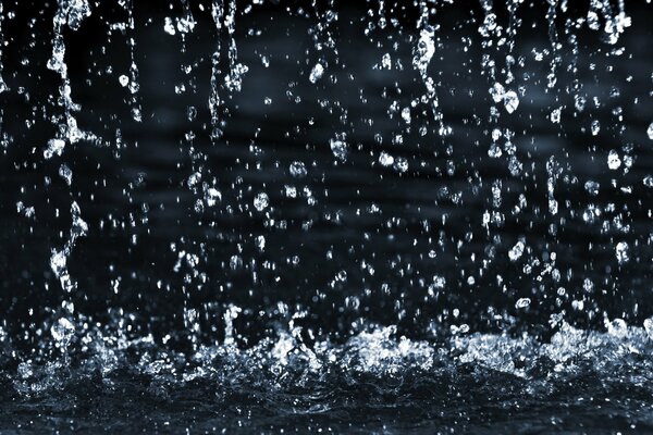 Splashes of water from above fall into a puddle