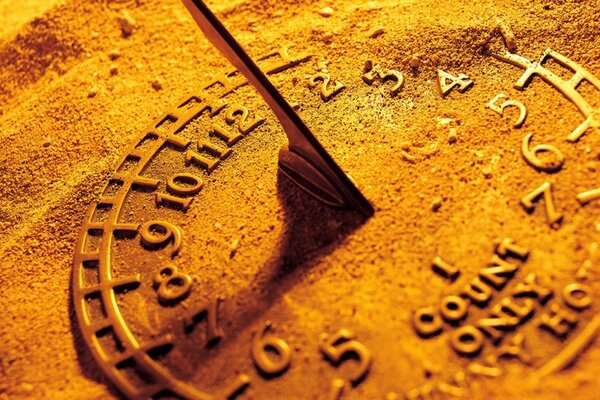 A sundial on the sand reminds of summer