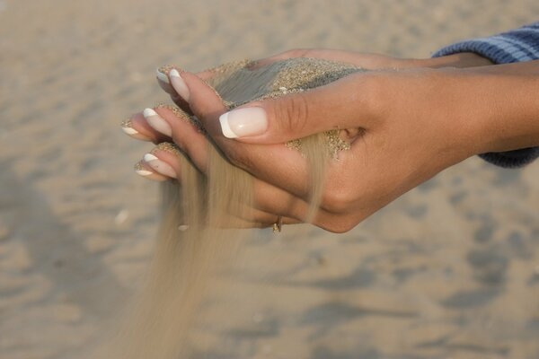 Fließender weißer Sand aus schönen Händen