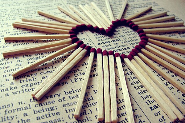 A heart made of matches on a book, newspaper