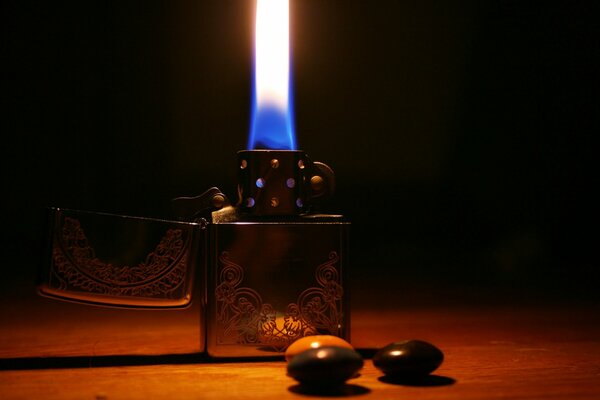 Briquet en métal avec une lumière allumée, debout sur une table dans une lueur orange