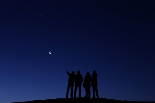 Silhouetten von Menschen, die den Mond betrachten