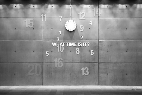 Un orologio con numeri e una frase è appeso al muro