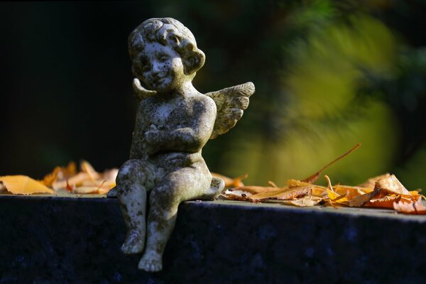 Escultura de un ángel entre las hojas de otoño