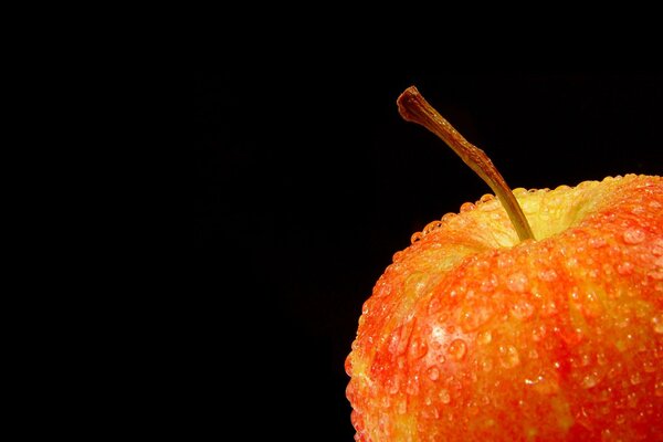 Apfel mit Tropfen auf schwarzem Hintergrund