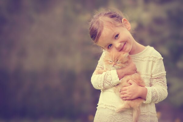 Cute red-haired girl with a kitten in her hands