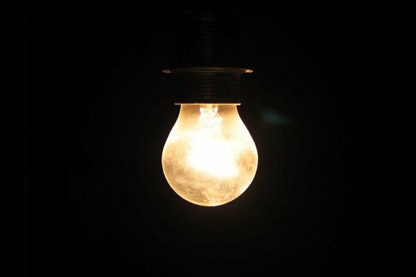 A burning light bulb on a black background