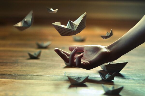 Main avec des bateaux en papier origami