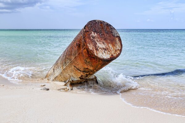 A metal pipe sticking out of the sand on the sea