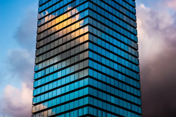 Стеклянное высотное здание с отражением облаков