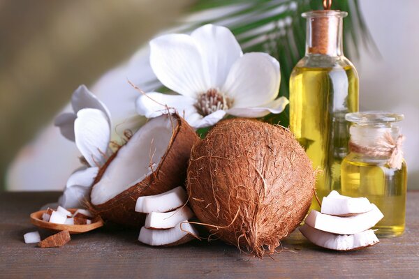 Cocos, flores blancas y aceite aromático en el fondo de una hoja de palma