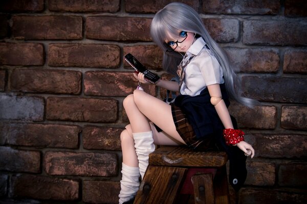 A doll girl with a phone in her hand and glasses