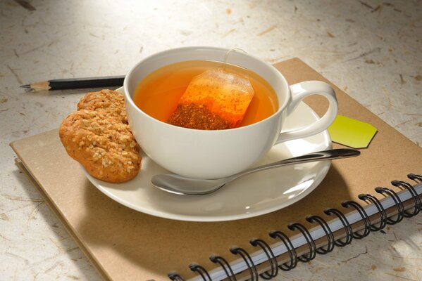 Tasse de thé avec des biscuits sur blacknote avec un crayon