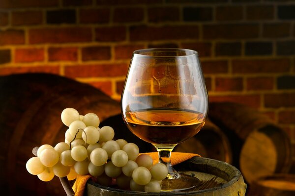 Amber-golden cognac in a glass and grapes