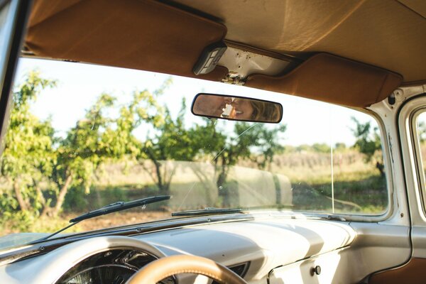 Coche retro con vistas al paisaje y el reflejo de la pareja en el espejo