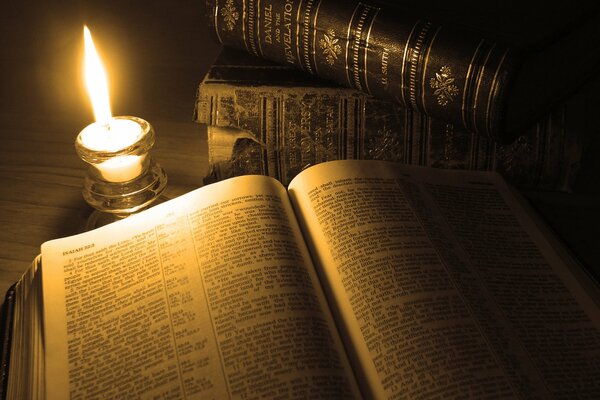 Огонь от свечи освещает страницы книги