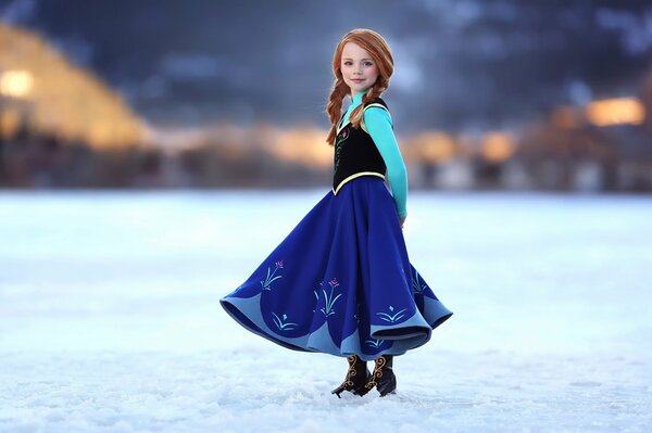 Little red-haired girl in a sundress in the snow