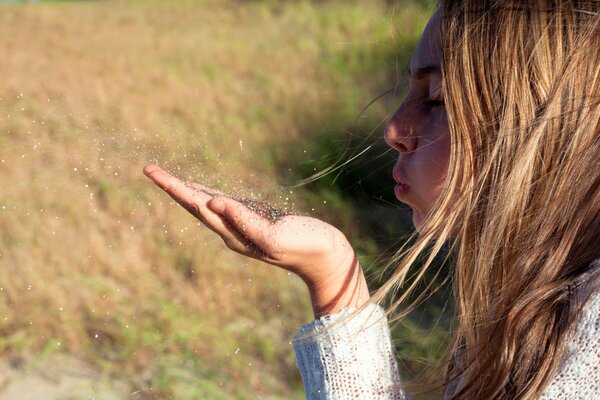 Souffler les filles sur la paume avec des grains de sable