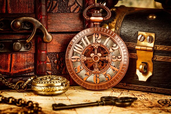 Antique clock standing on the table. There is a pocket watch and an old key nearby