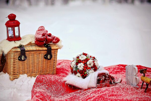 Amour. mariage en hiver. bouquet de mariée avec Rowan rouge. lampe de poche rouge et mitaines sur panier en osier