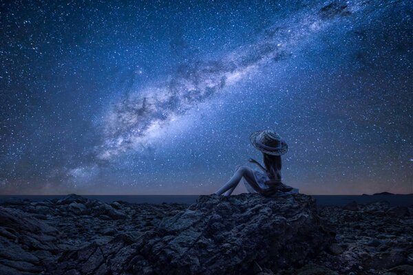 Girl on the rocks on the background of the sea under the night sky