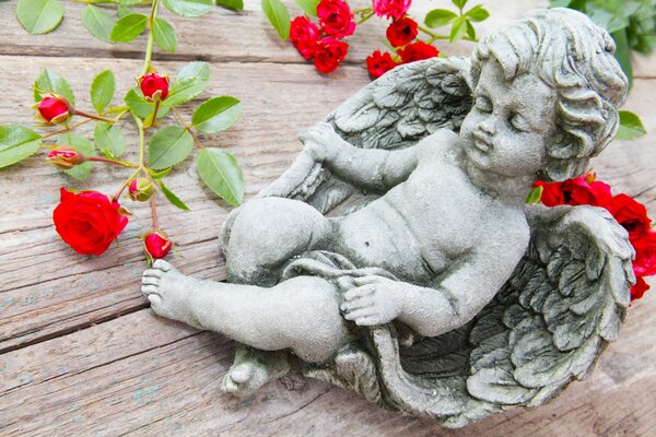 Cupid s angel figurine on the table with red roses