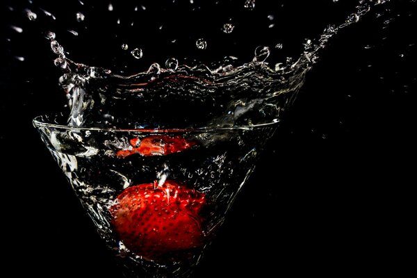Strawberries in a glass on a black background with splashes
