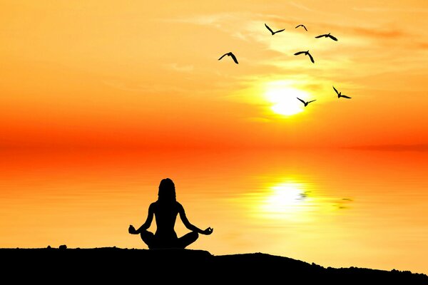 A meditating man in the rays of the sun on the seashore