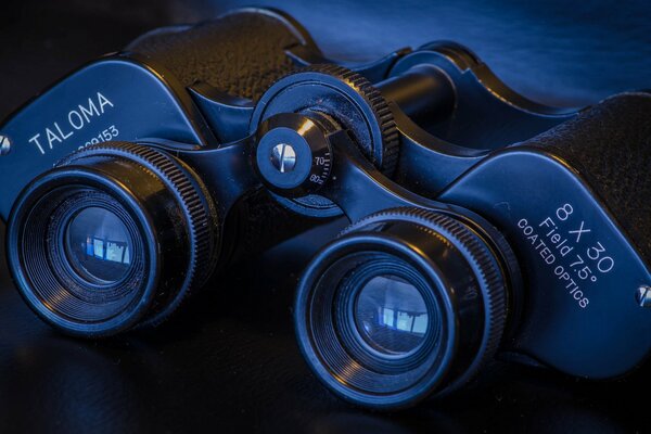 Black binoculars with optics on a macro background