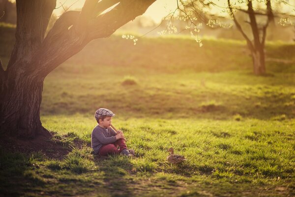 Ragazzo sulla natura ai raggi del sole che gioca su una pipa per un anatra