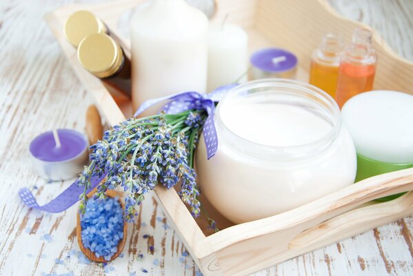 Una rama de lavanda atada con una cinta que se encuentra entre las velas junto a una cucharada de sal de baño Marina