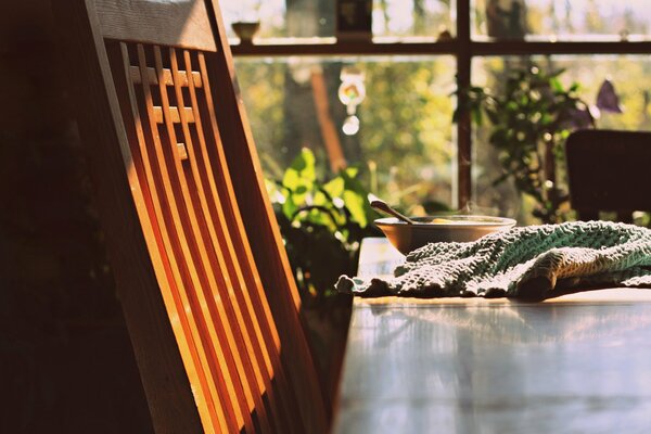 Una silla de madera junto a la mesa donde se sirve el Desayuno bajo el sol naciente