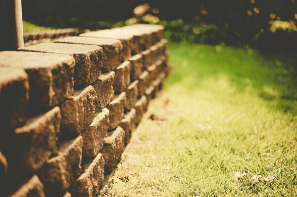 Stone wall on a background of green grass