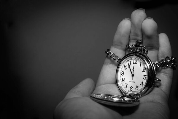 Watch with a chain in the palm of your hand black and white image