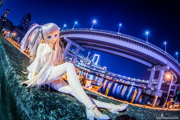 Bambola giocattolo sul ponte del lungomare nella città di notte