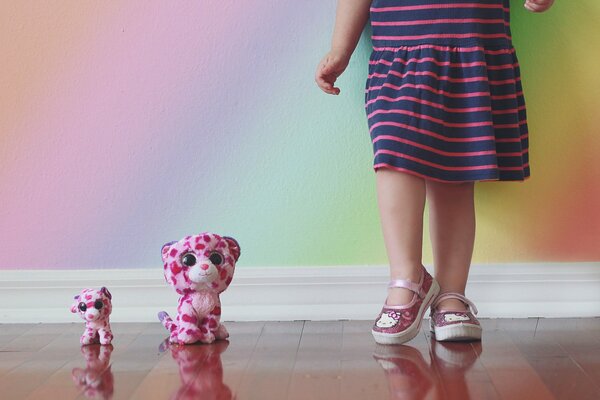 Deux jouets à côté des pieds de la jeune fille près du mur