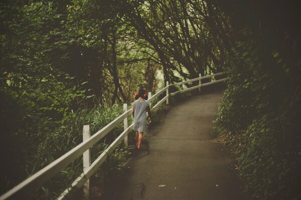 A girl walks along a forest path