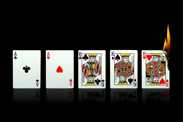 Four playing cards, one of which is lit on a black background