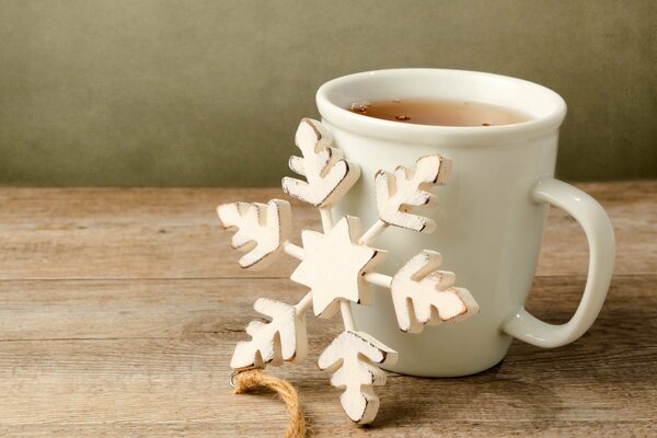 Eine Tasse Tee und eine hölzerne Schneeflocke