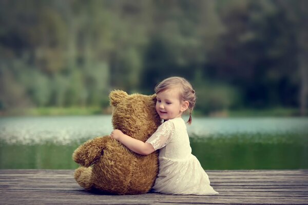 A girl with a bear on the lake shore